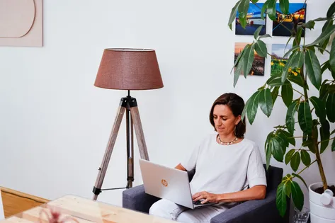 Anja sitzt mit Laptop im Sessel und verwaltet Adressen mit CentralStationCRM.