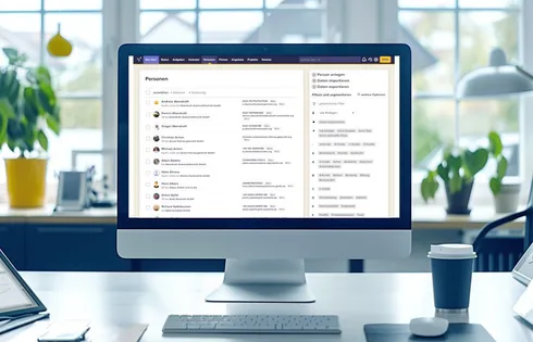 Ein Bildschirm, der CentralStationCRM zeigt. Im Hintergrund ein großes Bürofenster und einige Pflanzen.
