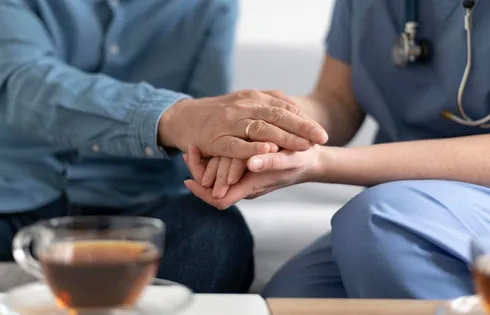 Symbolbild Altenpflege, Pflegerin hält Hände eines alten Mannes.